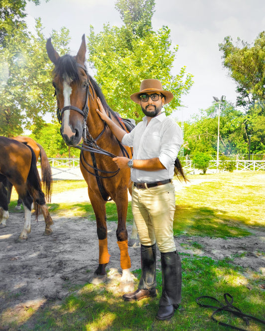 boy in white dress shirt riding brown horse during daytime