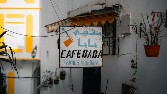 A sign for cafe baba hangs on a white wall.