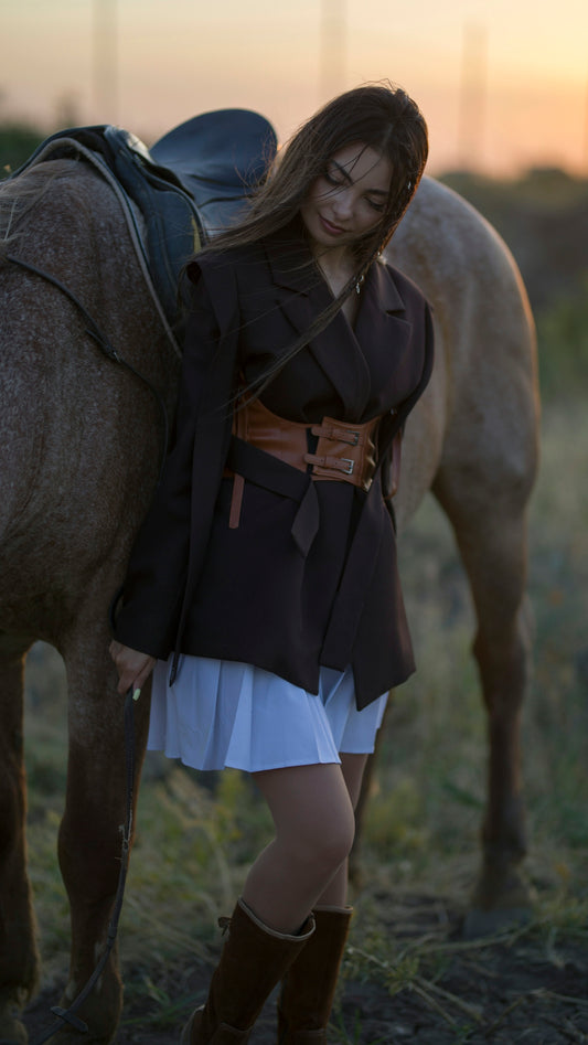 A woman poses beside a horse at dusk.